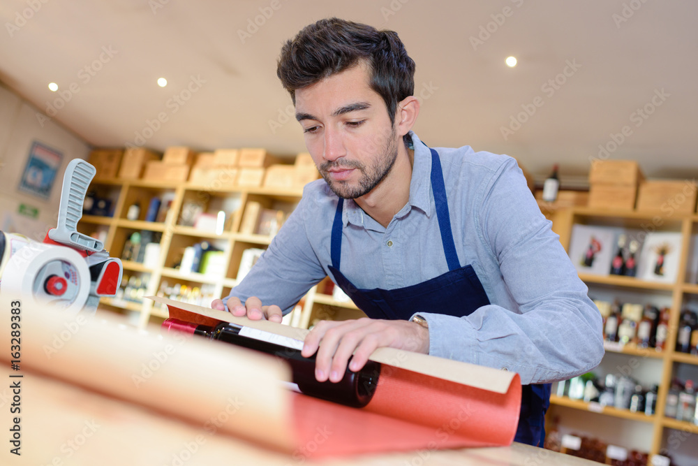 Obraz premium Shop clerk wrapping bottle of wine