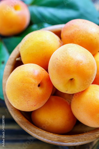 Ripe apricots in a wooden bowl closeup.