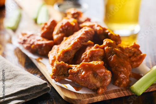 sauced buffalo chicken wings on wooden board with celery