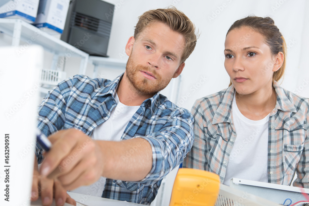 Male technician teaching female counterpart Male technician teaching female counterpart