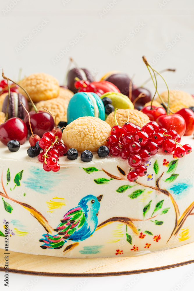 Cake with hand painted colorful birds and fresh berries