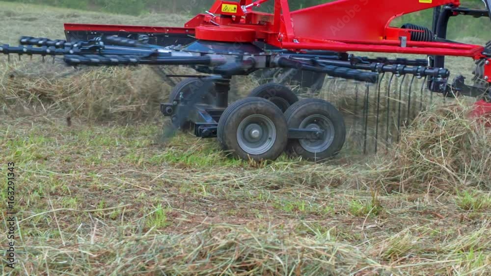Rotary rakes are slowly moving when a man is preparing hay on a hill somewhere up in the mountains. Rotary rakes are slowly moving when a man is preparing hay on a hill somewhere up in the mountains.