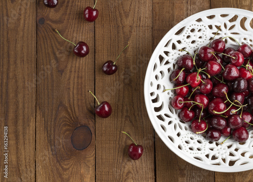 Ripe sweet cherry on a laсe bowl. Wooden Background. Flat lay. Top view photo