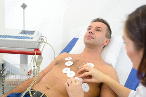 Nurse attaching heart monitor pads to man's chest