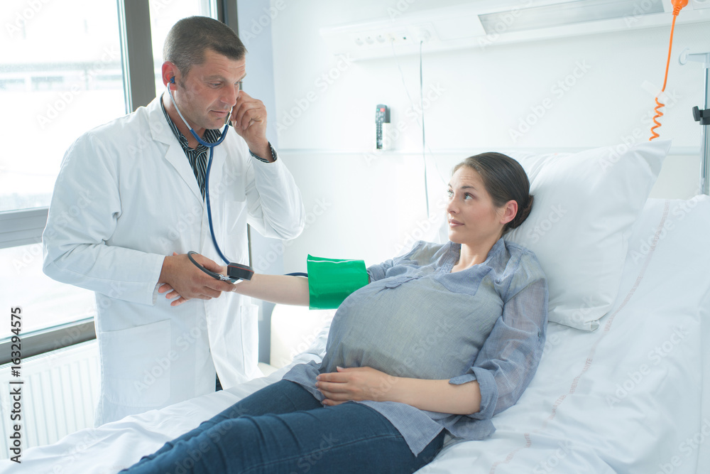 Obraz premium Doctor taking pregnant woman's blood pressure
