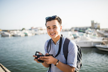 Young asian man look at taked photo in travel near marina in old city