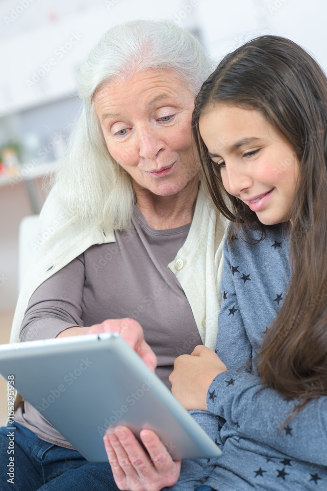 Elderly and young females looking at tablet computer Elderly and young females looking at tablet computer