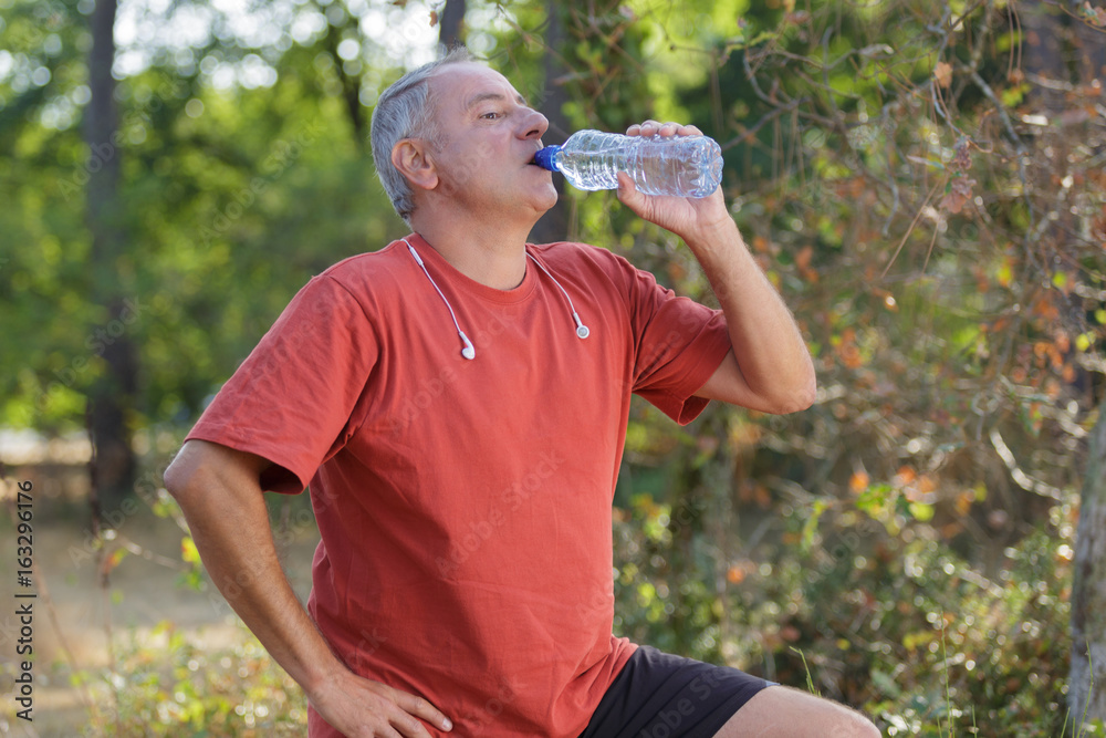 Middle aged man drinking water from bottle Middle aged man drinking water from bottle