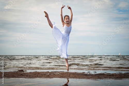 Маленькая балерина, ребенок,  прыгает на фоне моря, белая юбка развивается как парус.