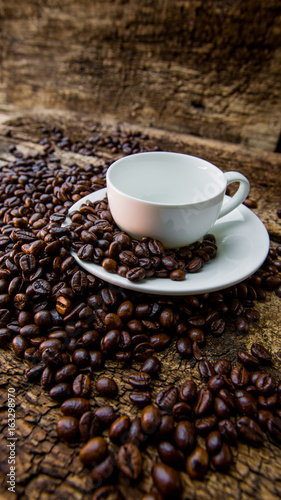 Coffee beans in a white mug. Coffee beans on a wooden background. Dark background.