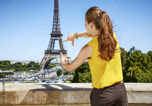 young woman framing with hands in front of Eiffel tower in Paris © Alliance
