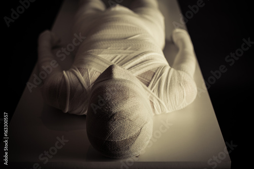 Slika na platnu Young mummy displayed on table in darkness