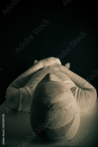 Young mummy laid on table in the darkness