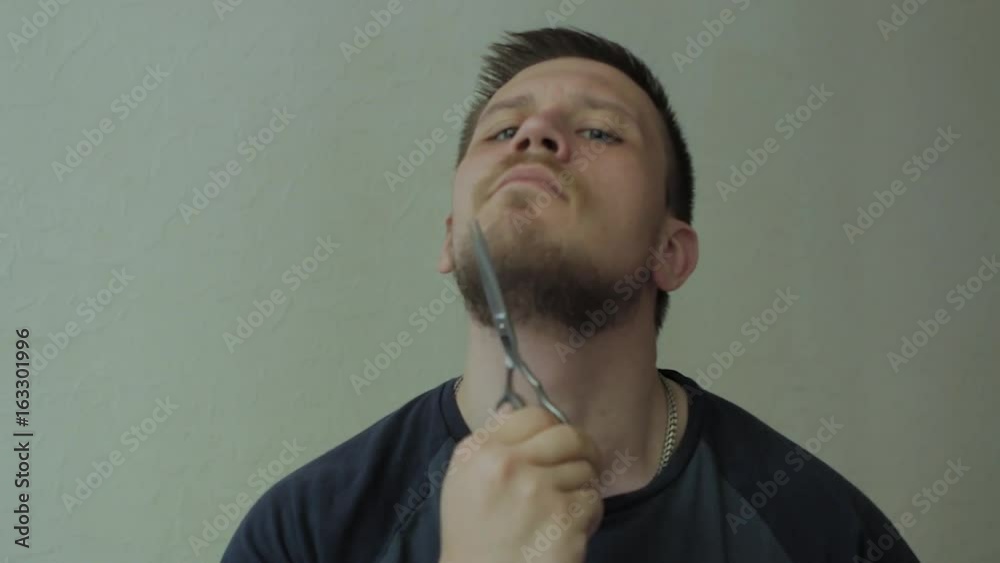 Man cutting his beard with scissors.