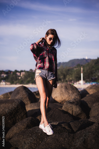 Sexy Girl in flannel shirt on the rocky beach.