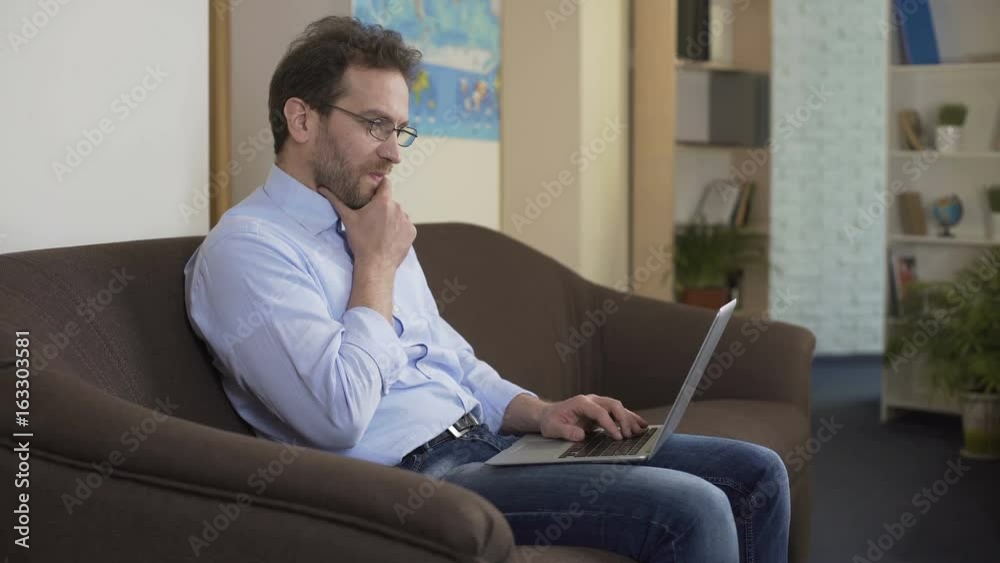 Serious man with laptop thinking how to make extra money, modern technologies Serious man with laptop thinking how to make extra money, modern technologies