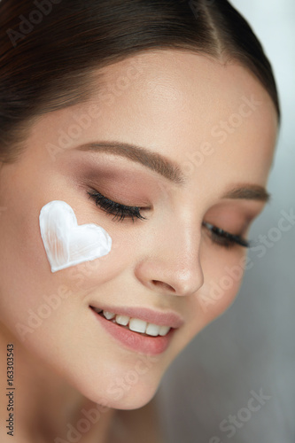 Woman Beauty Face Cosmetics. Female With Cream Heart On Skin
