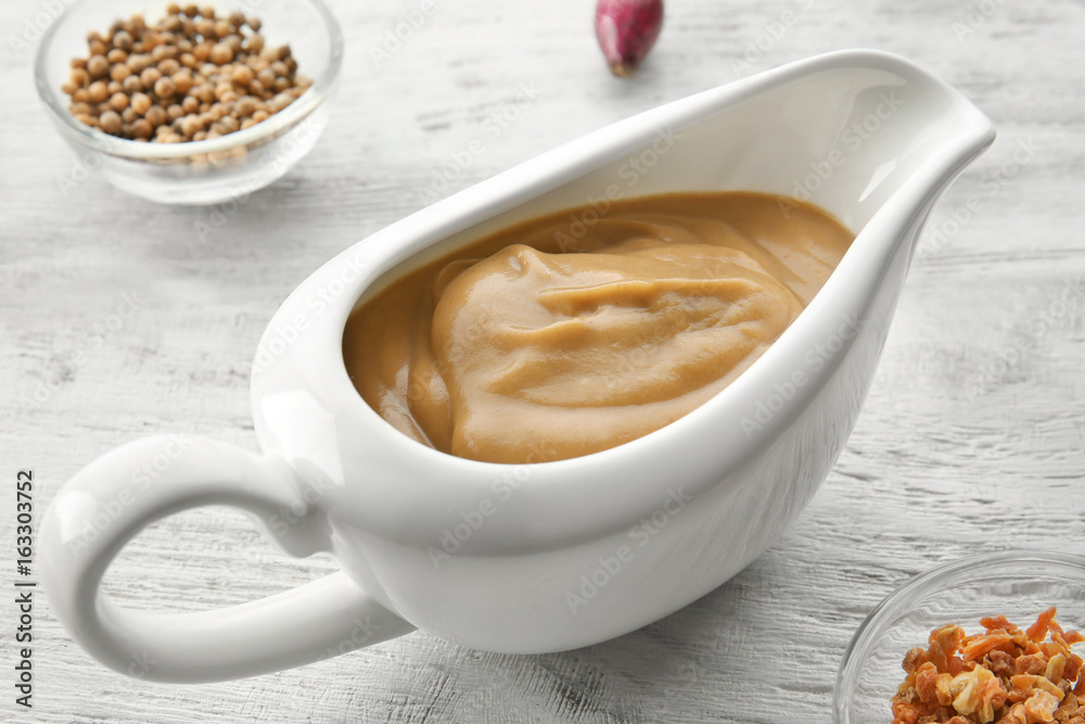 Sauce boat with turkey gravy and spices on wooden table Sauce boat with turkey gravy and spices on wooden table