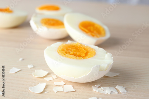 Sliced hard boiled eggs in shell on wooden surface. Nutrition concept