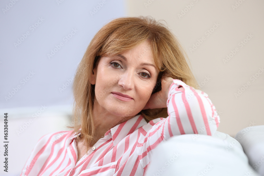 Naklejka premium Attractive mature woman resting on sofa at home
