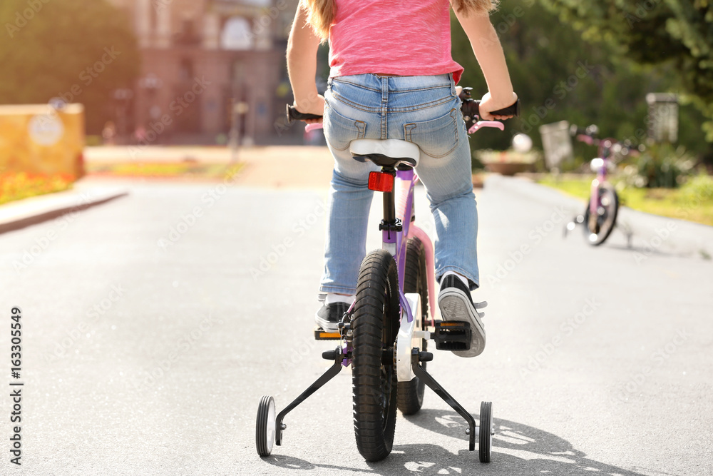 Fototapeta premium Cute little girl riding bicycle outdoors on sunny day