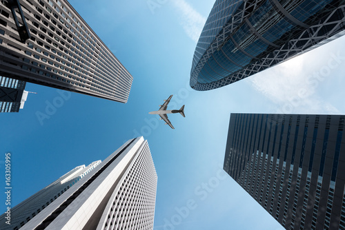 Photography Tokyo skyscrapers buildings and a plane flying overhead at in Tokyo Shinjuku downtown and business district in morning at Tokyo, Japan