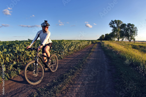 smiling cyclist rides along a field trail.