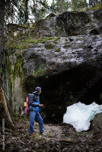 Young man hiking in scandinavia landscape. Rocks hidden in the forest. Karelia outdoors travel destination.