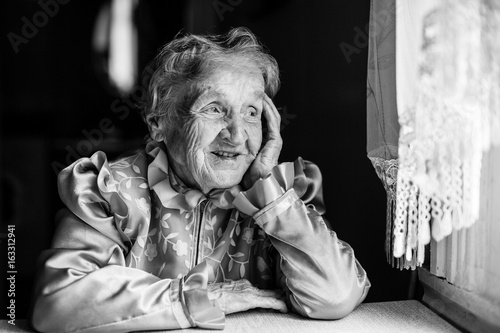 Elderly lady sits at the ta...