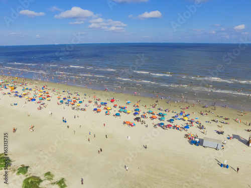 Aerial view beach shoreline on sunny summer day with people bathing, sunbathing, playing volley and relax in Galveston, Texas. Colorful umbrellas, lounge chairs. Holiday maker, summer vacation concept © trongnguyen