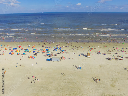 Aerial view beach shoreline on sunny summer day with people bathing, sunbathing, playing volley and relax in Galveston, Texas. Colorful umbrellas, lounge chairs. Holiday maker, summer vacation concept © trongnguyen