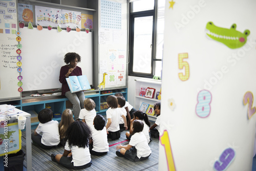 Kindergarten students sitting on the floor listening to story telling