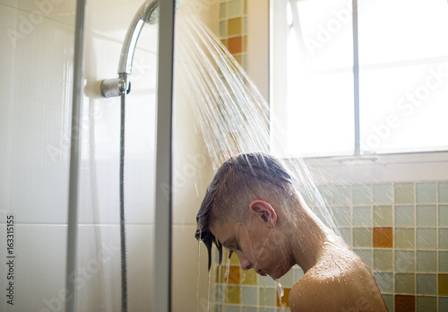 Obraz na plátne Young caucasian man showering in bathroom