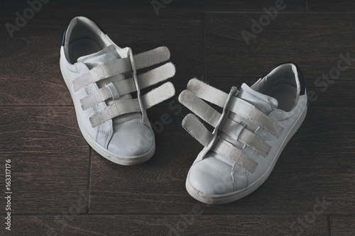 Pair of white, worn-out shoes on velcro