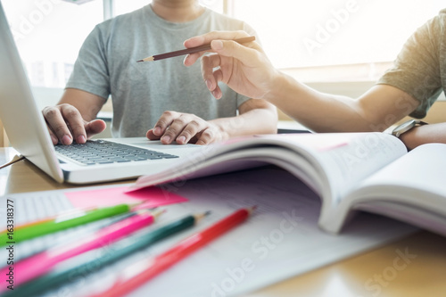 Teaching helping technology concept. Woman young teacher or tutor with adult students in classroom at desk with papers, laptop computer. Studies course