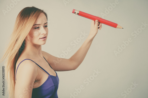 Blonde woman holds big pencil in hand drawing