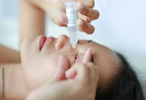 Closeup view of woman applying eye drop. photo