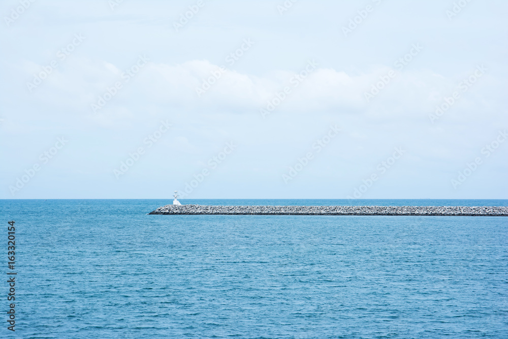 Breakwater (pier) with small lighthouse. The construction wall in the port to protect the ships from sea waves.