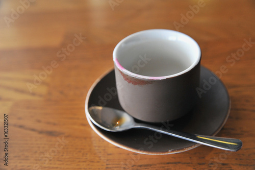 Fototapeta Naklejka Na Ścianę i Meble -  A cup of coffee stands on a brown table in a cafe. A cup of beautiful and fragrant latte with a slice of sugar - a refined sugar and tubules is on the table in a cafe. Cafe inside with visitors and la