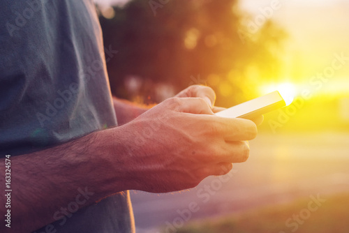 Man using mobile phone on street in sunset