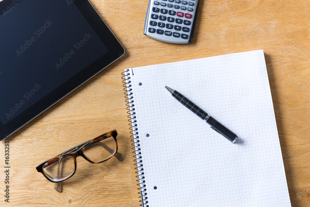 Work desk with tablet, glasses, calculator and notepad on wooden table Work desk with tablet, glasses, calculator and notepad on wooden table