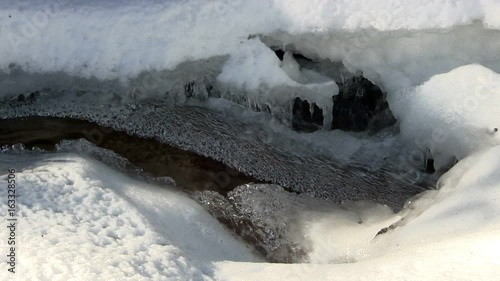 A mountain stream flows under the ice at Diane's bath in Bartlett, New Hampshire.  Interesting shapes of ice and snow are carved by the rushing mountain water.  Includes audio.  photo