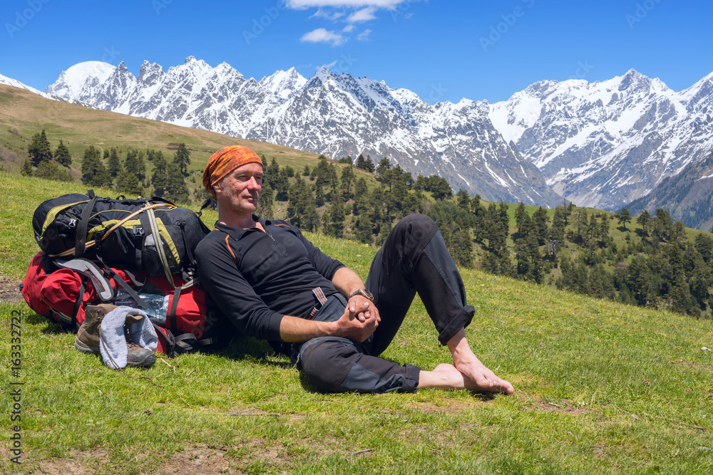 Tired man traveler relaxed, lying on the alpine meadow