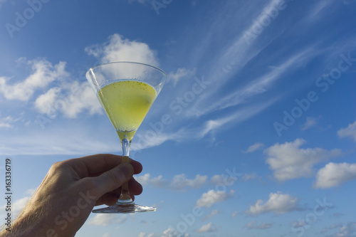 Fresh cocktail held against blue sky