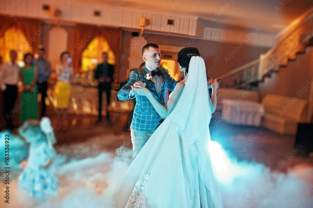 Beautiful wedding couple dancing their first dance in a restaurant with people in the background. Beautiful wedding couple dancing their first dance in a restaurant with people in the background.