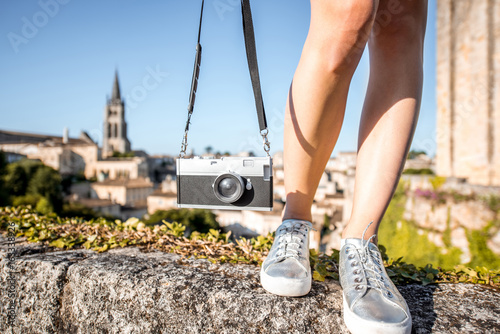 Woman holding a photo camera on the saint Emilion village background in France
