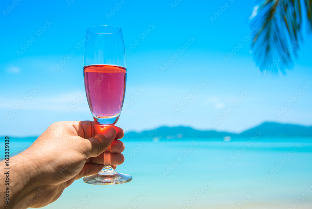 Man hand with glass of champagne by the sea.
