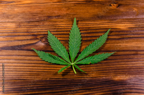 Leaf of the cannabis plant on wooden table. Top view