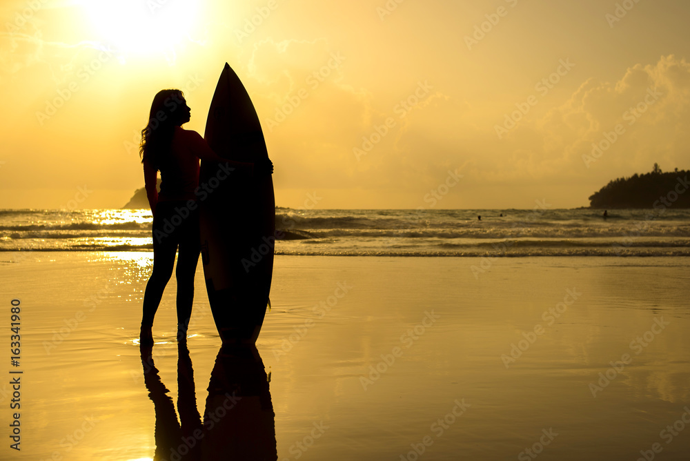 Silhouette Of girl with surfboard on sunset beach.Phuket,Thailand.