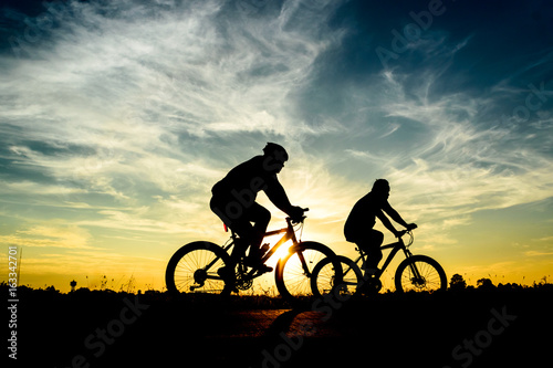 Silhouette of cyclist riding on  bike at sunset. © Pattadis